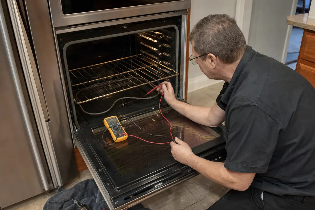 Technician testing the bake element of an open double wall oven with a multimeter, the oven racks visible in the picture - How to Find the Model and Serial Number on a Built-In